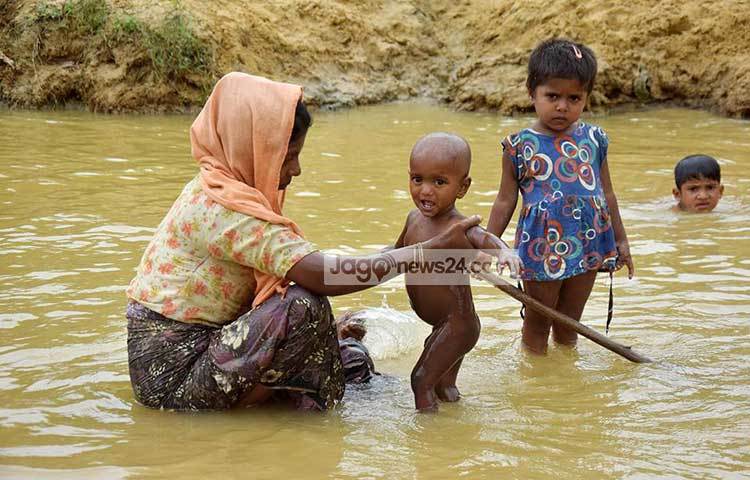 সন্তানকে গোসল করাচ্ছেন এক রোহিঙ্গা মা। ছবি : মাহবুব আলম