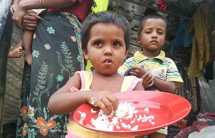 এক মুঠো ভাত কী তৃপ্তি নিয়ে খাচ্ছে এক রোহিঙ্গা শিশু। ছবি : মাহবুব আলম