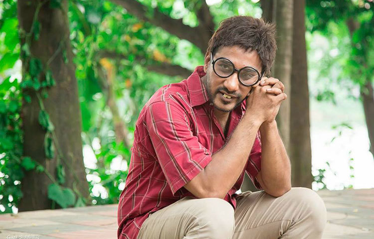 অভিনেতা সজলের এই ছবি দেখে সত্যি অচেনা লাগছে। প্রতিনিয়ত তিনি নতুন নতুন সব চরিত্রে অভিনয়ের চেষ্টা করছেন। সেই ধারাবাহিকতায় এবার নতুন রূপে দেখা দিলেন তিনি! দুটো বড় বড় দাঁত আর চোখে মোটা ফ্রেমের গোল চশমা সজলের চিরচেনা রূপ যেন পাল্টে দিয়েছে।