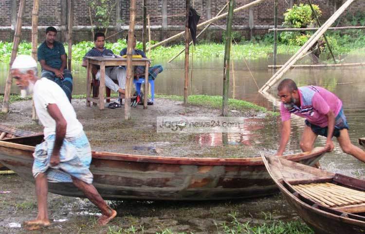 নৌকা ঠেলে হাটে তুলছেন দুই নৌকা বিক্রেতা। ছবি : মো. ছগির হোসেন