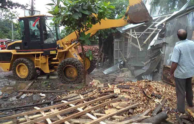 অবৈধ স্থাপনার মালিকদের এ ব্যাপারে মাইকিং করে তাদের দোকানপাট ও মালামাল সরিয়ে নেয়ার জন্য বারবার মাইকিং করলেও সেদিকে তারা গুরুত্ব না দেয়ায় সকালে বৃষ্টির মধ্যেই বুলডোজার দিয়ে স্থাপনা অপসারণ করা হয়। ছবি : হাসান মামুন