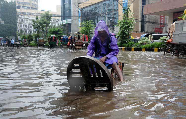ম্যানহোলের ঢাকনা তুলে দিয়ে পানি নিষ্কাশনের চেষ্টা করছে সিটি কর্পোরেশনের এক কর্মী। ছবি : বিপ্লব দিক্ষিৎ