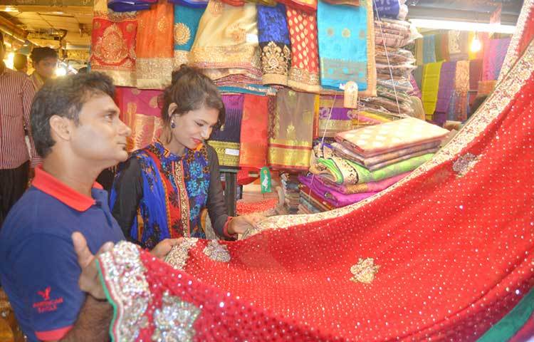 শাড়ি কিনতে ব্যস্ত একজন ক্রেতা। অনেক ক্রেতা মনে করছেন গত বছরের চেয়ে এবারের পোশাকে দাম বেশি। ছবি : বিপ্লব দিক্ষিৎ
