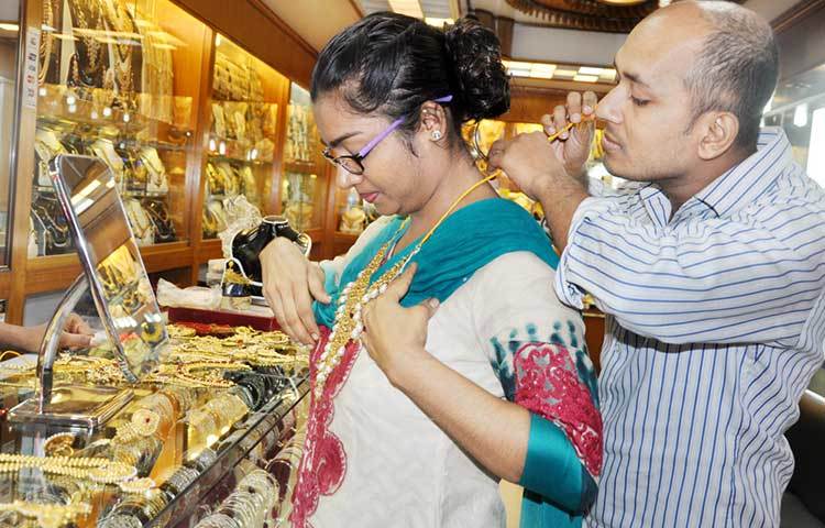পছন্দের গহনা বাছাই করছেন এই নারী। দোকানী তাকে গহনা পরিয়ে দিতে সাহায্য করছেন। ছবি : বিপ্লব দিক্ষিৎ