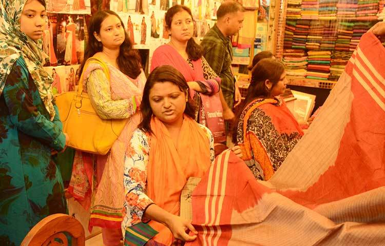 শাড়ির দরদাম করছেন এই ক্রেতা। মার্কেট ঘুরে দেখা গেছে এবারের ঈদে বেশির ভাগ নারীই শাড়ি কিনছেন। ছবি : বিপ্লব দিক্ষিৎ