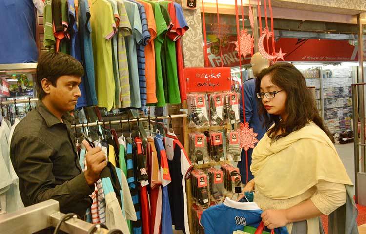 ক্রেতাকে পোশাক দেখাচ্ছেন এই দোকানী। সেই সঙ্গে পোশাকের গুণাগুণ বর্ণনা করছেন ক্রেতার কাছে। ছবি : বিপ্লব দিক্ষিৎ