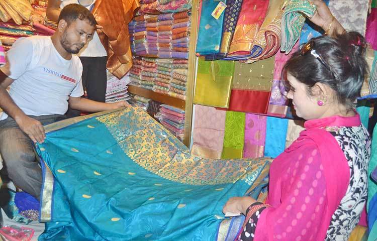 শাড়ি পছন্দ করতে ব্যস্ত এক নারী। এবারের বাজারে ভারতীয় বা পাকিস্তানি কাপড়ের তুলনায় দেশি কাপড়ের দাম তুলনামূলক কম। ছবি : বিপ্লব দিক্ষিৎ 