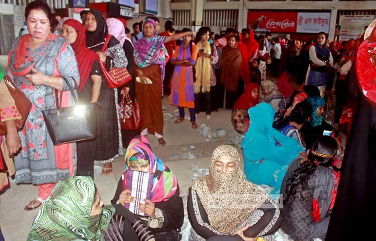 নারী টিকিট সংগ্রহকারীদের দীর্ঘ লাইন। দাঁড়িয়ে থাকতে থাকতে অনেকে ক্লান্ত হয়ে মেঝেতে বসে পড়েছেন। ছবি : বিপ্লব দিক্ষিৎ