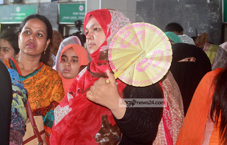 টিকিট কাটার লাইনে দাঁড়িয়ে গরমের হাত থেকে মুক্তি পেতে হাত পাখা দিয়ে বাতাস করছেন এক নারী। ছবি : বিপ্লব দিক্ষিৎ