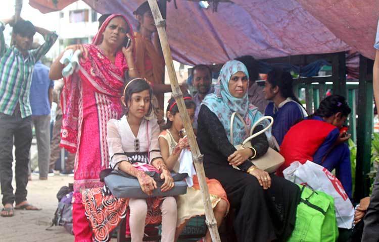 নারী ও শিশুরা মহাখালীর বাস টার্মিনালে বাসে ওঠার অপেক্ষায় রয়েছে। গরম আবহাওয়া তাদের কিছুটা ভোগান্তির সৃষ্টি করছে। ছবি : বিপ্লব দিক্ষিৎ