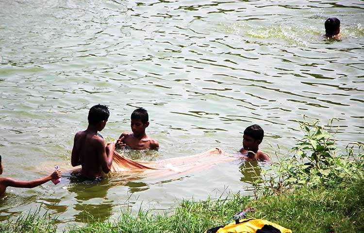 জাল দিয়ে হাতিরঝিলে মাছ ধরছে শিশুরা। ছবি : রবিউল ইসলাম পলাশ