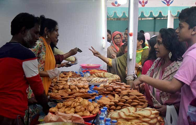পিঠা বিক্রর ধুম পড়েছে। প্রত্যেককে যেন পিঠার স্বাদ নিতেই হবে। ছবি : মাহবুব আলম