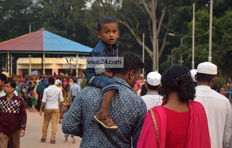 কাঁধে চড়ে শিশুপার্কে ঘুরে বেড়াচ্ছে শিশুটি। আহারে মিষ্টি শৈশব। ছবি : মাহবুব আলম