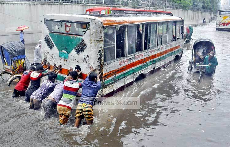 পানিতে ডুবে বাসটি বিকল হয়ে গেছে। তাই ঠেলে মেরামতের জন্য নিয়ে চেষ্টা করছেন বাসের লোকজন। ছবি : বিপ্লব দিক্ষিৎ