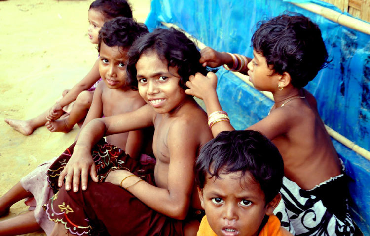 এক রোহিঙ্গা শিশু অন্য এক শিশুর মাথার চুল বিলি কেটে দিচ্ছে। ক্যামেরা দেখে তারা অনেক উচ্ছ্বল হয়ে উঠলো। ছবি : বিপ্লব দিক্ষিৎ