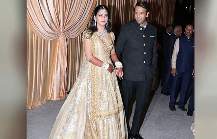 রিসেপশনের দিন সোনালি ও আইভরি রঙের ডিজাইনার লেহঙ্গায় সেজেছিলেন ঈশা। সোনালি-রুপালি ফ্লোরাল মোটিফ আঁকা এই লেহঙ্গা ভারতীয় কোনও ডিজাইনারের বানানো নয়। সুদূর ইতালির ফ্যাশন হাউজ ‘ভ্যালেন্তিনো’ তার জন্য এই বিশেষ পোশাক বানিয়েছেন। আনন্দের পরনে ছিল কালো জমকালো স্যুট। দু’জনকেই খুব সুন্দর দেখাচ্ছিল এই দিন।