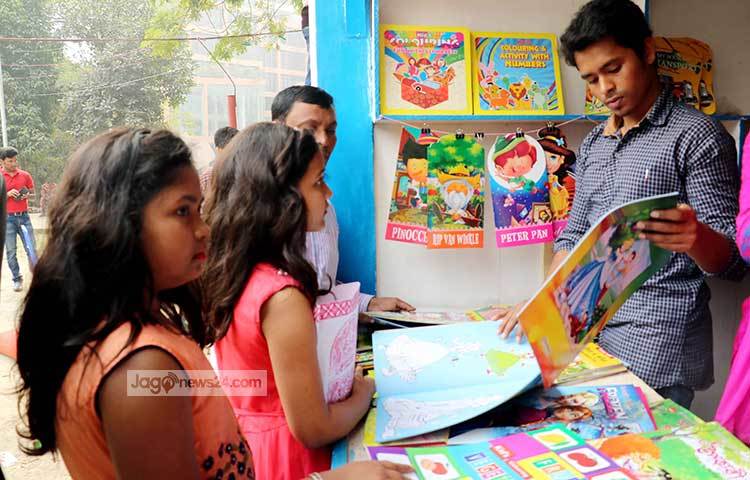শিশুদেরকে বিভিন্ন রকমের বই দেখাচ্ছেন এই স্টলের বিক্রয়কর্মী। ছবি : বিপ্লব দিক্ষিৎ