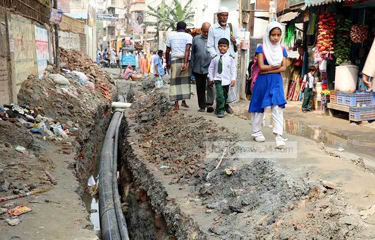 খোঁড়াখুঁড়ি করা রাস্তা দিয়ে স্কুলে যাচ্ছে ছাত্র-ছাত্রীরা যাচ্ছে। ছবি : বিপ্লব দিক্ষিৎ