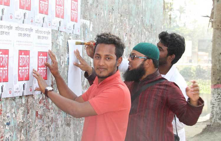 শরীয়তপুরে ‘জাতিসংঘে বাংলা চাই’ শীর্ষক পোস্টার লাগানো হচ্ছে। ছবি : ছগির হোসেন