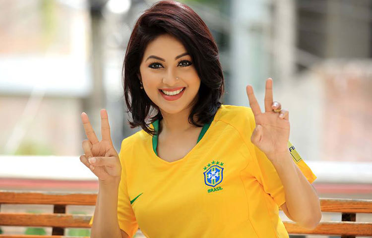 হাসি আর ব্রাজিলের জয়ের চিহ্ন দর্শকদের দেখাচ্ছেন মোনালিসা।