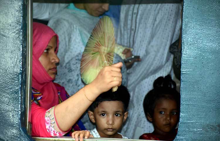 বাড়ি ফেরার যাত্রায় অন্যতম বিড়ম্বনার নাম হচ্ছে প্রচণ্ড গরম। গরমের হাত থেকে বাঁচতে এই নারী তার সন্তানদের হাতপাখা দিয়ে বাতাস করছেন। ছবি : বিপ্লব দিক্ষিৎ