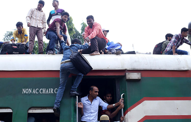 এক যাত্রীকে টেনে ছাদে তুলছে অন্য যাত্রীরা। ঝুঁকি মেনেও তারা হাসি মুখে বাড়ি যাচ্ছেন সবাই। ছবি : মাহবুব আলম