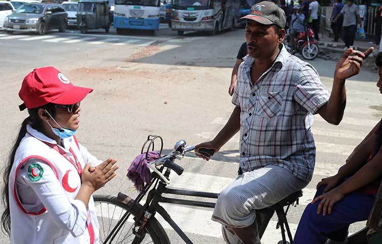 রিকশা চালকদের রাস্তায় চলার নিয়ম মেনে চলাচলের জন্য নির্দেশনা দিচ্ছে রেড ক্রিসেন্টের এক সেচ্ছাসেবী। ছবি : মাহবুব আলম