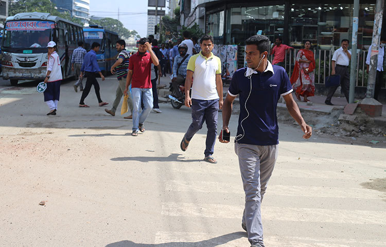 রাজধানীর বাংলা মোটর মোড়ের দৃশ্য। কানে হেড ফোন লাগিয়ে রাস্তা পার হচ্ছেন এক পথচারী। এতে করে যে কোনো সময় দুর্ঘটনায় পড়তে পারেন তিনি। ছবি : মাহবুব আলম