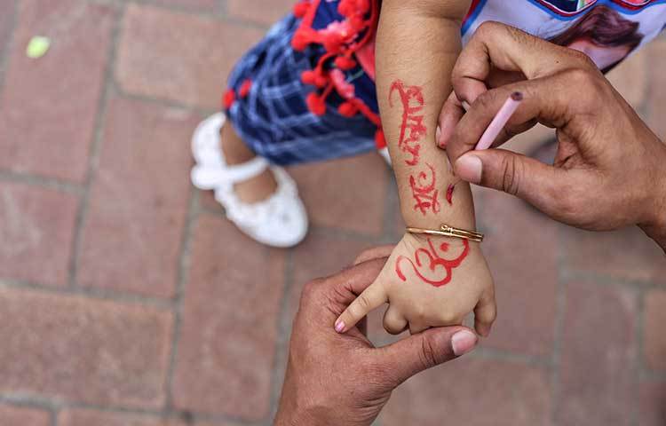 শ্রীকৃষ্ণের জন্মদিন উপলক্ষে শিশুর হাতে আপলনা আঁকা হচ্ছে। ছবি : মাহবুব আলম