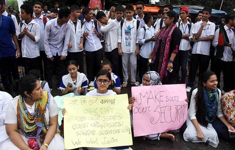 বিভিন্ন স্লোগান লেখা প্লাকার্ড নিয়ে রাস্তায় বসে আছে শিক্ষার্থীরা। ছবি : বিপ্লব দিক্ষিৎ