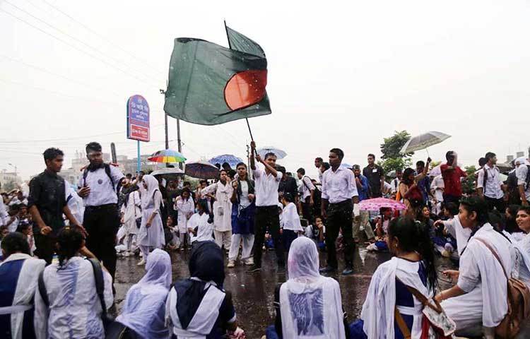 বৃষ্টিতে ভিজে জাতীয় পতাকা উড়িয়ে দাবি আদায়ে আন্দোলন করে যাচ্ছে শিক্ষার্থীরা। ছবি : বিপ্লব দিক্ষিৎ