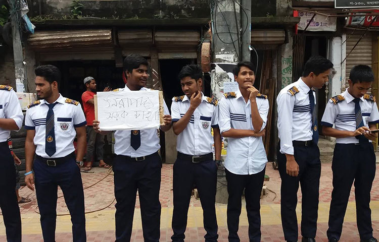 ‘নিরাপদ সড়ক চাই’ প্লাকার্ড নিয়ে দাঁড়িয়েছে শিক্ষার্থীরা।