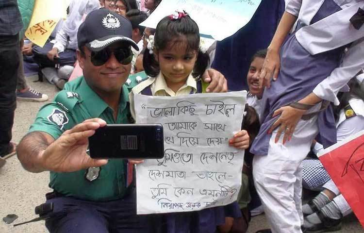 নিরাপদ সড়কের দাবিতে রাস্তায় নেমে আসা শিশু সঙ্গে সেলফি তুলছেন এক পুলিশ অফিসার।