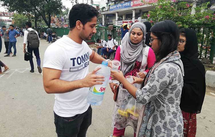 আন্দোলনরত শিক্ষার্থীদের আনারস ও পানি দিচ্ছেন এক অভিভাবক। ছবি : মাহবুব আলম