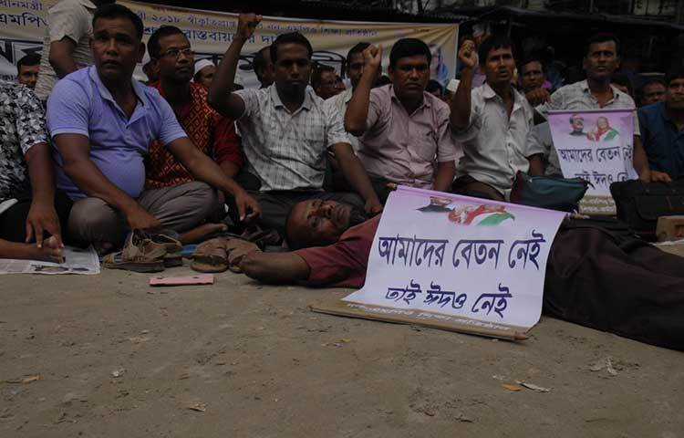 ‘আমাদের বেতন নেই তাই আমাদের ঈদও নেই’-লেখা প্লাকার্ড নিয়ে রাস্তায় শুয়ে আছেন একজন শিক্ষক। ছবি : বিপ্লব দিক্ষিৎ