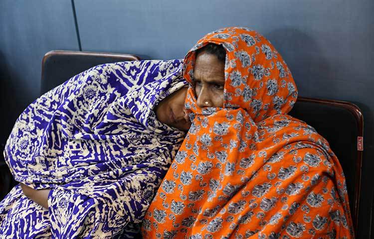 কষ্ট যেন তাদের পিছু ছাড়ছে না। সহায়তা নিতে আসা ক্লান্ত এক নারী আর এক নারীর গায়ে ভর করে বসে আছেন। ছবি : মাহবুব আলম