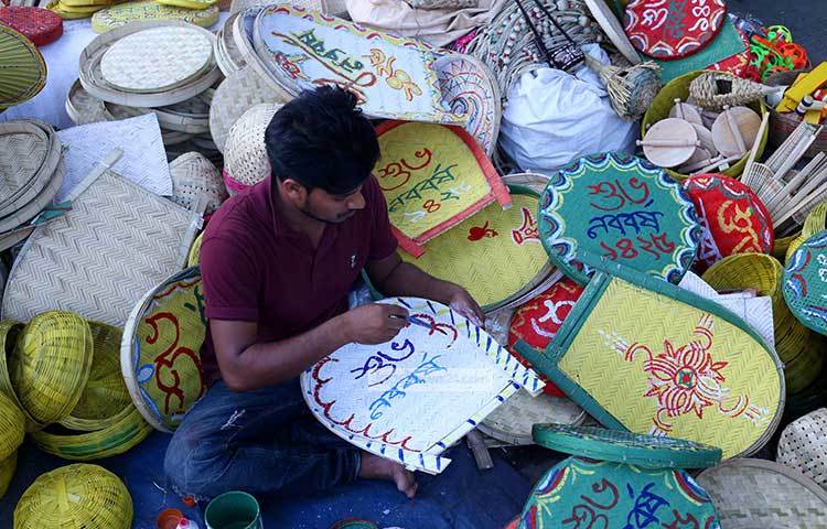 নতুন বছরের আগমনের বার্তা কুলোতে লিখছেন এক শিল্পী। ছবিটি রাজধানীর শিশু একাডেমীর সামনে থেকে তোলা হয়েছে। ছবি : মাহবুব আলম
