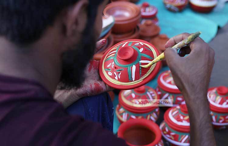 মটির সরাকে শিল্পীর তুলিতে নিপুণ করে সাজিয়ে তোলা হচ্ছে। ছবি : মাহবুব আলম