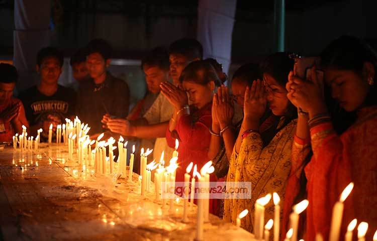 মোমবাতি জ্বালিয়ে প্রার্থনা করছেন বৌদ্ধ সম্প্রদায়ে লোকজন। ছবি : মাহবুব আলম