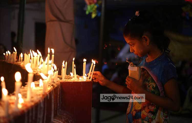 একটি শিশু মোমবাতি জ্বালিয়ে স্মরণ করছে বুদ্ধকে। ছবি : মাহবুব আলম