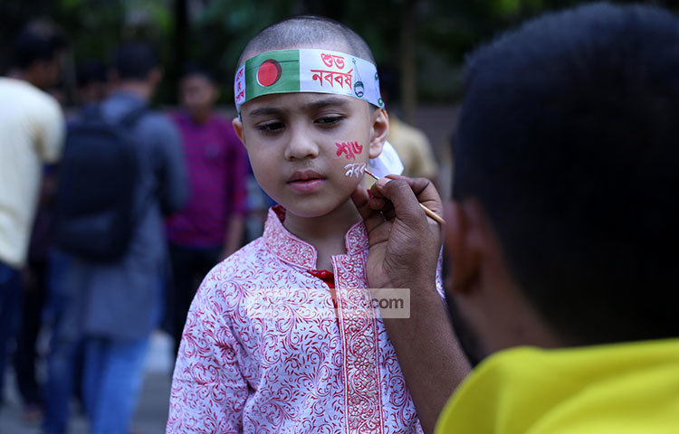 শিশুটির গায়ে শুভ নববর্ষের আলপনা এঁকে দিচ্ছে এক শিল্পী। ছবি : মাহবুব আলম