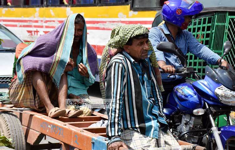 গরমের মাঝে ঠেলাগাড়ি চালাতে গিয়ে ক্লান্ত হয়ে পড়েছে শ্রমিকরা। রোদ থেকে দুই শ্রমিক বাঁচার চেষ্টা করছে। ছবি : বিপ্লব দিক্ষিৎ