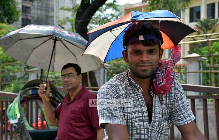 প্রখর রোদ থেকে রক্ষা পেতে এই রিকশা চালক ছাতা লাগিয়েছেন। ছবি : বিপ্লব দিক্ষিৎ
