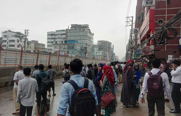 রাস্তায় পানি আটকে পড়ায় গাড়ি চলছে না রাস্তায়। তাই অফিসগামী লোকজন গাড়ির অপেক্ষায় আছেন। ছবি : আবু সালেহ সায়াদাত