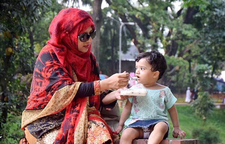 সন্তানকে নিয়ে ঘুরতে এসেও সন্তানের প্রতি যত্নের ঘাটতি নেই এক বিন্দু। সন্তানকে খাওয়ানোর কাজে ব্যস্ত মা। ছবি : মাহবুব আলম