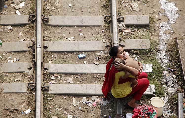 রেল লাইনের পাশে বসবাস করেন এই। ছিন্নমূল জীবনেও সন্তানের প্রতি মায়ের ভালোবাসার কমতি নেই। ছবি : মাহবুব আলম