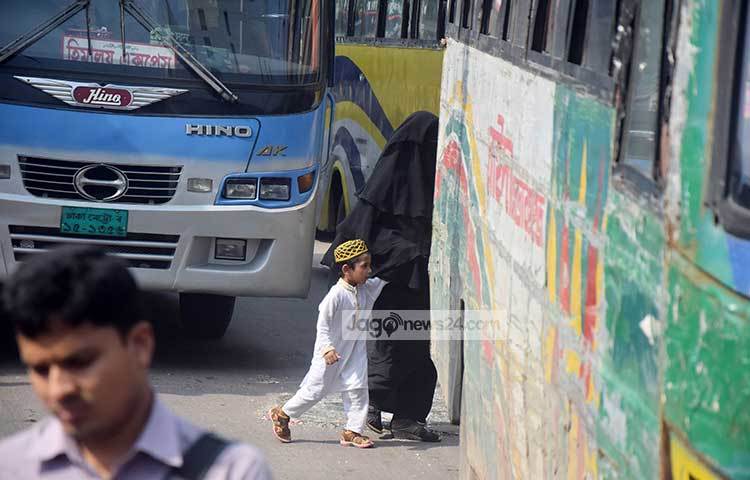 দ্রুত পথ চলতে গিয়ে এক নারী শিশুটিকে নিয়ে পাশাপাশি ছুটে চলা গাড়ির মধ্য দিয়ে রাস্তা পার হচ্ছেন। ছবি : মাহবুব আলম