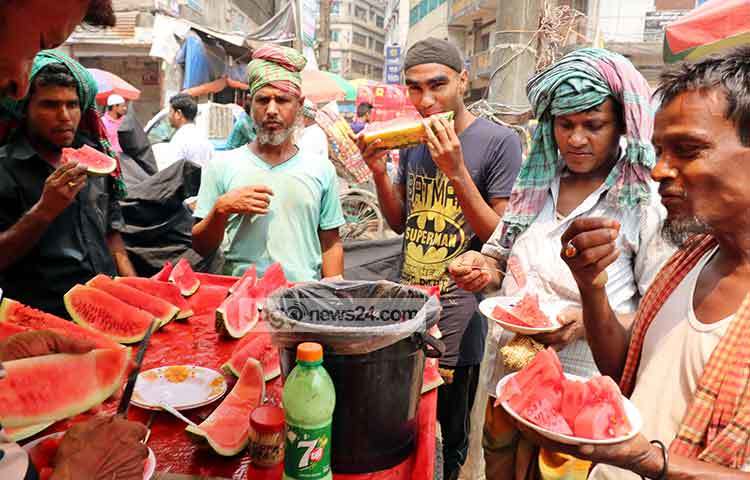 স্বল্প আয়ের কর্মজীবী মানুষ কাটা তরমুজ খেয়ে পিপাসা মেটাচ্ছে। ছবি : বিপ্লব দিক্ষিৎ