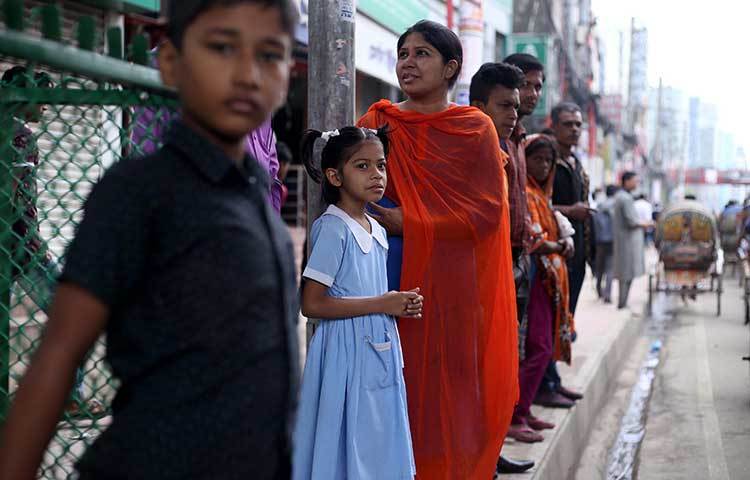 গাড়ির অপেক্ষায় দাঁড়িয়ে আছেন অনেকে। ছবি : মাহবুব আলম