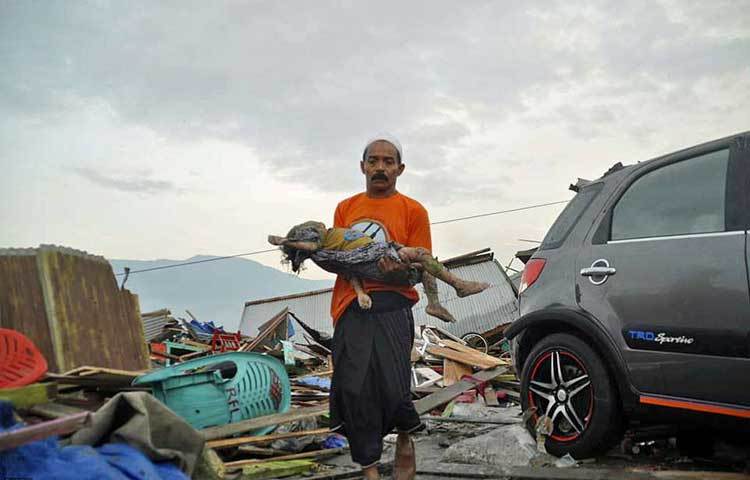 নিহত একটি শিশুকে ধ্বংসস্তূপের ভেতর থেকে উদ্ধার করে নিয়ে যাওয়া হচ্ছে।